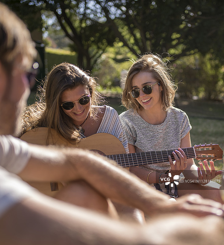 女人在院子里一边弹吉他一边聊天图片素材