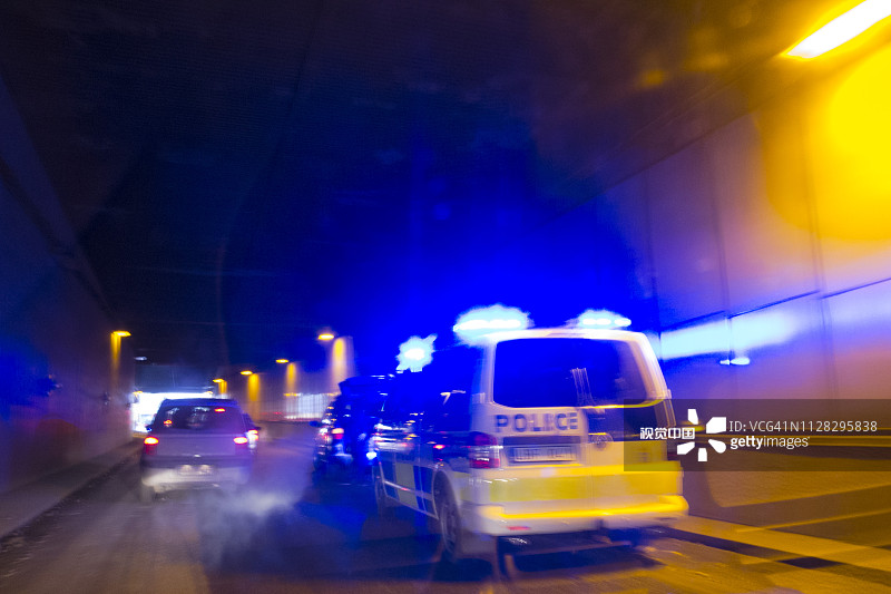 隧道里警车开着蓝色的灯追赶一辆车图片素材
