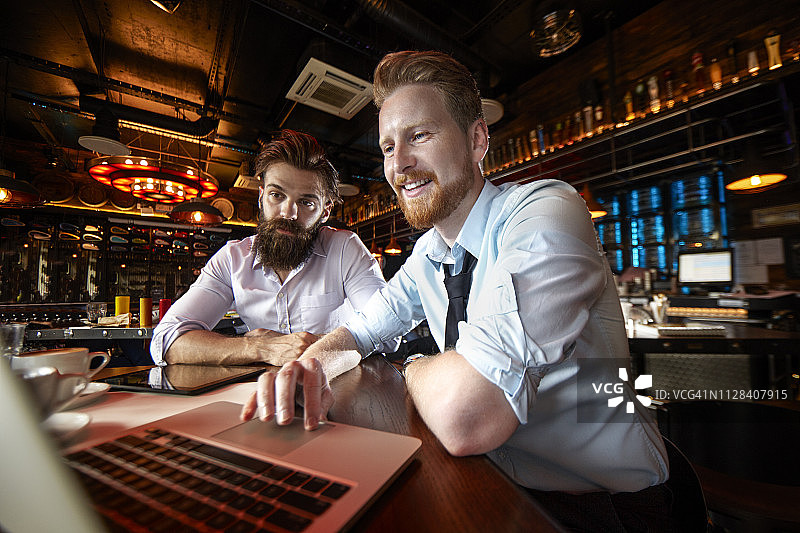两个商人在咖啡馆里一起用笔记本电脑工作图片素材