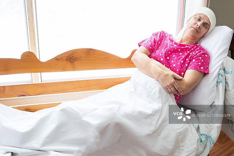 一个身患癌症的白人妇女躺在床上睡觉。图片素材