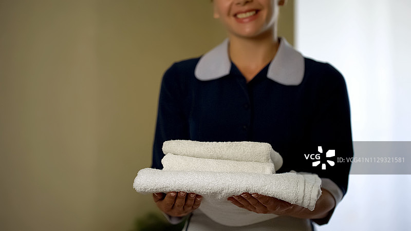 微笑的酒店工作人员展示干净的枕头，良好的清洁，健康标准图片素材