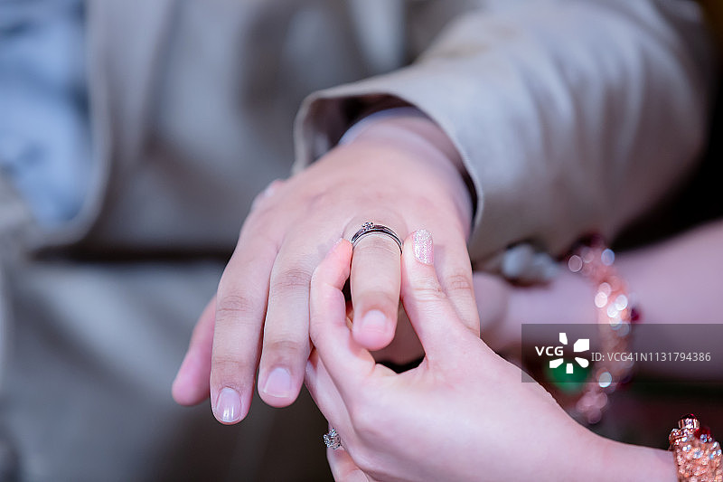 结婚戒指。她给他戴上了结婚戒指。近距离新娘给新郎戴上戒指。泰式婚礼和泰式婚礼装饰。图片素材