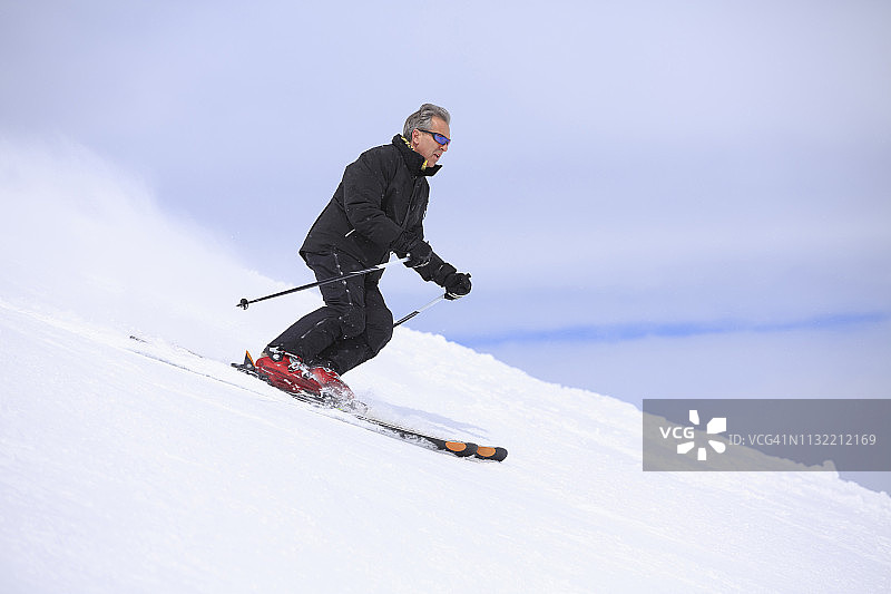 业余冬季运动高山滑雪。男子滑雪者在阳光明媚的滑雪场滑雪。高山雪景。利维尼奥，阿尔卑斯山，欧洲，意大利。图片素材