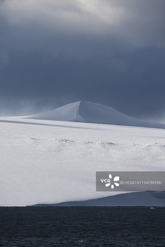 雪覆盖的海岸景观与风暴云，欣洛彭海峡，在nordaustlanddet和斯匹次卑尔根，斯瓦尔巴群岛，挪威图片素材