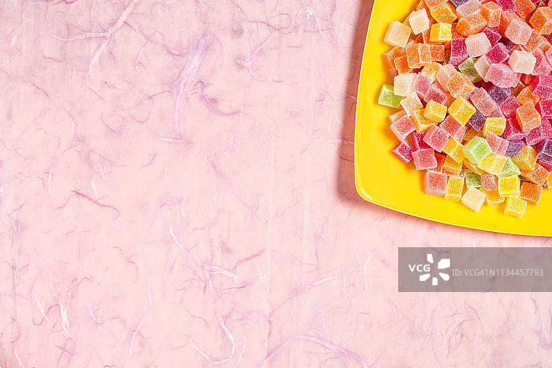 糖果和果冻在彩色盘中，粉红色的背景图片素材