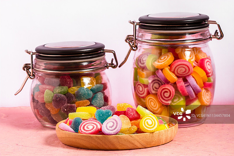 糖果和果冻五颜六色的木盘子在粉红色的背景图片素材