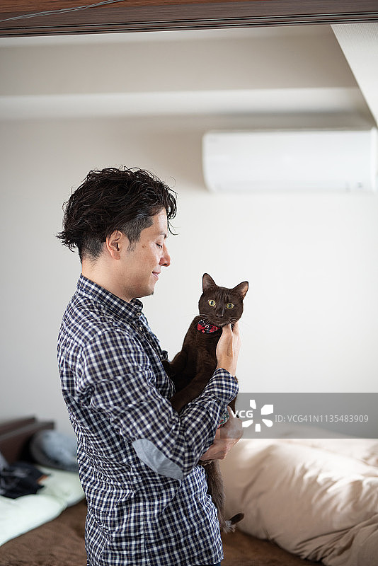 一个男人在卧室抱着一只猫图片素材
