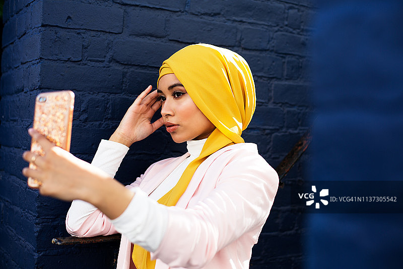 年轻的穆斯林妇女使用电话图片素材