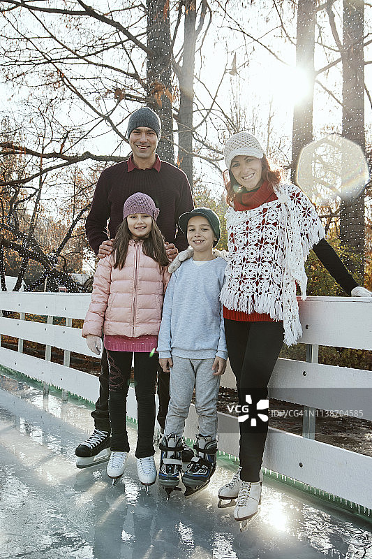 一家人靠在溜冰场的栏杆上图片素材