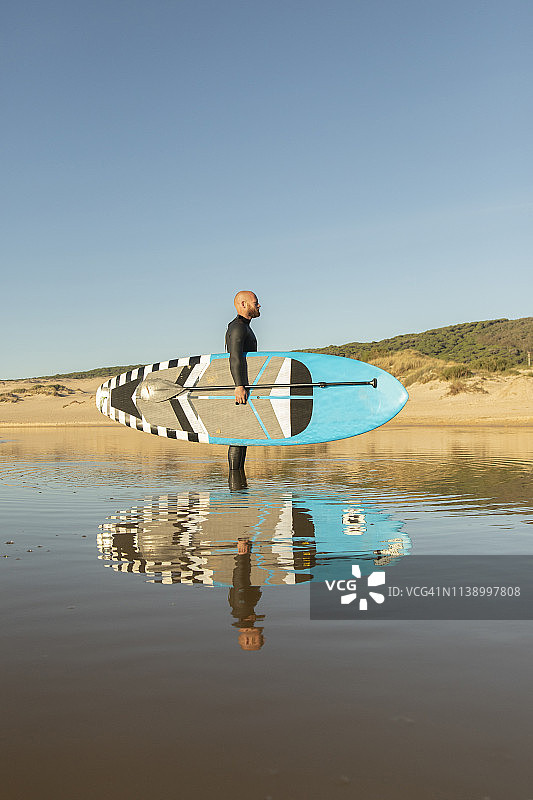 西班牙，安达卢西亚，塔里法，一名男子手持立式桨板在海上图片素材