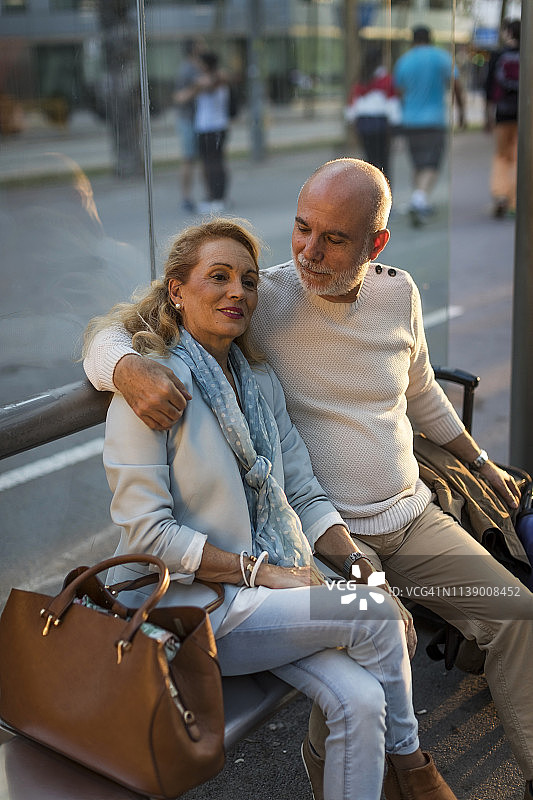 西班牙巴塞罗那，一对老年夫妇带着行李坐在城市的电车站图片素材