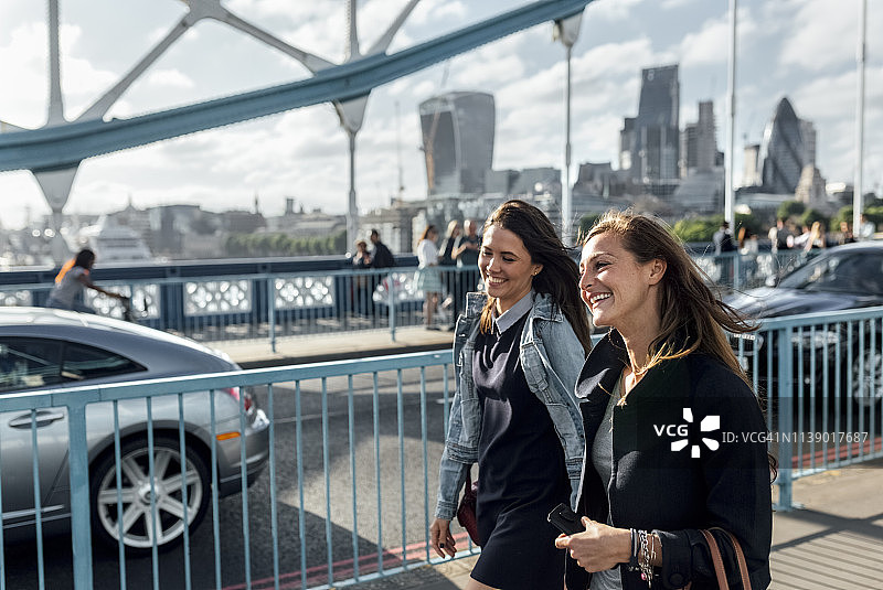 英国，伦敦，两个快乐的女人走在塔桥上图片素材