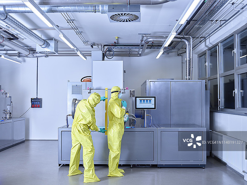 在工业实验室工作的化学家，穿着防护服在无尘室工作图片素材