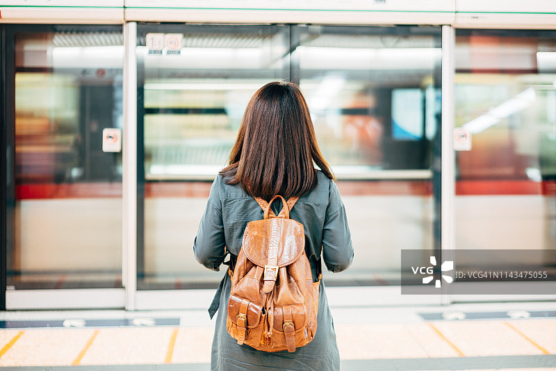后视图的年轻女子旅客等待列车地铁车站在香港城市，中国图片素材