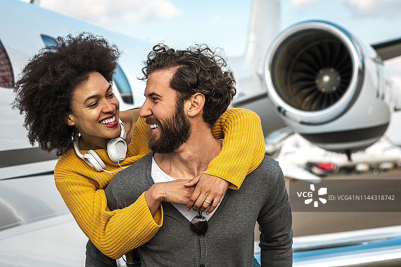 一名年轻的成功女子在一架停在机场跑道上的私人飞机旁深情地拥抱她的伴侣图片素材