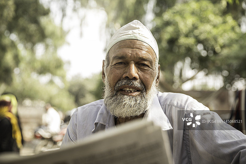 在户外看报纸的印度老人图片素材