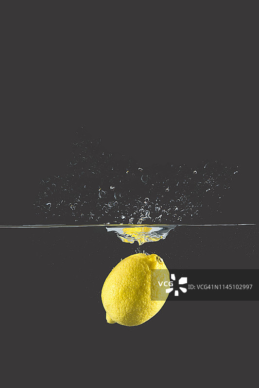 黄色的柠檬掉落并溅起水来图片素材
