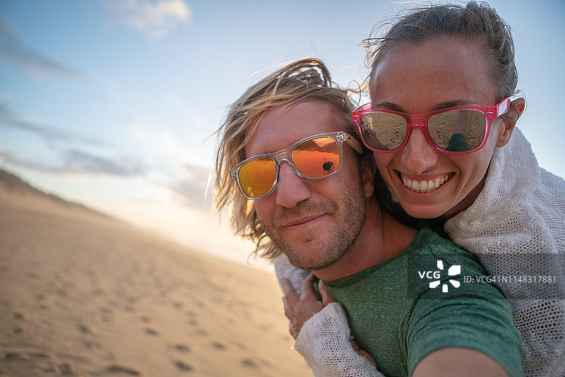 年轻夫妇在美丽的海滩上拍摄有趣的自拍照片-凉爽的度假概念-威基基，夏威夷，美国。图片素材