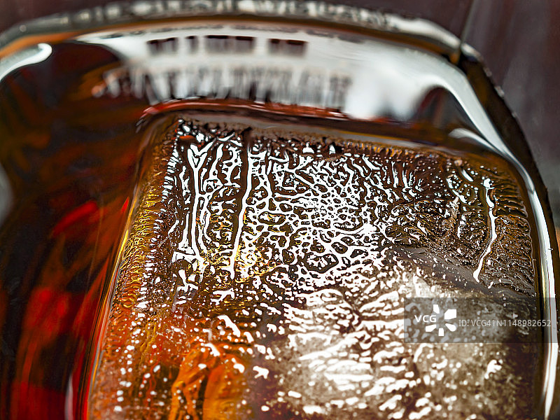 大冰块在一杯威士忌和可乐饮料。冰纹理细节。图片素材