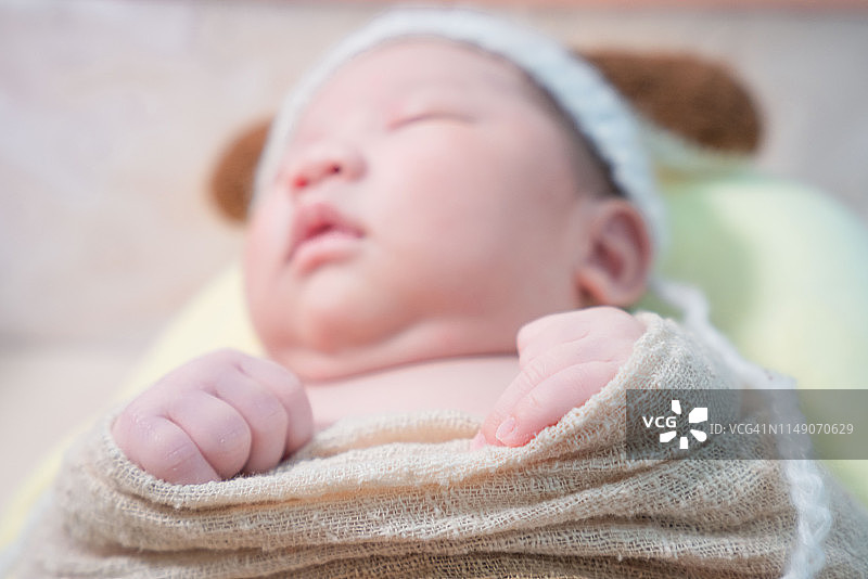 一个亚洲新生儿裹着布睡觉图片素材