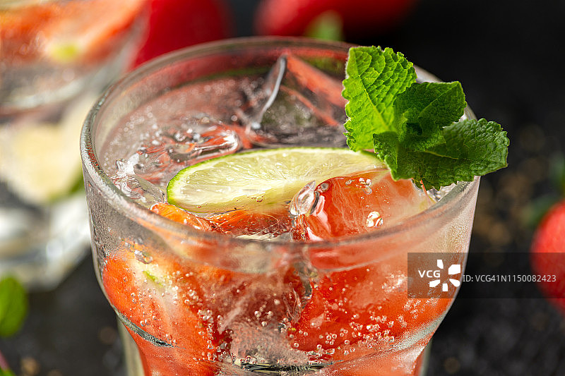 草莓莫吉托鸡尾酒与朗姆酒，酸橙和薄荷玻璃杯。夏天喝冷饮加冰图片素材