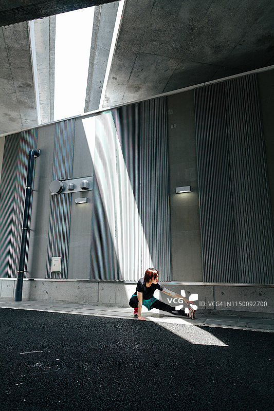 女运动员在城市里伸展她的双腿图片素材