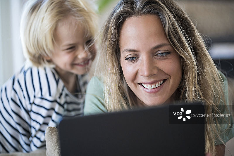 微笑的母亲和儿子在家里使用平板电脑图片素材
