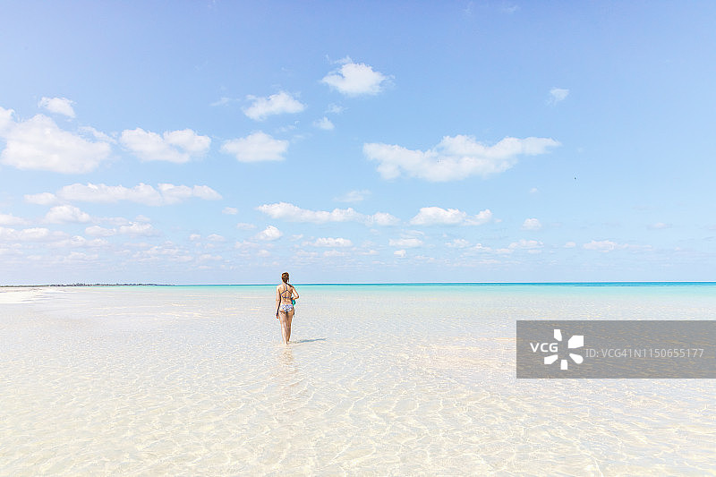一名年轻女子在墨西哥霍尔鲍克斯岛清澈的海水中漫步图片素材