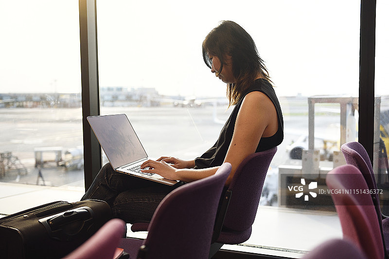 商务女性在等待航班时使用笔记本电脑图片素材