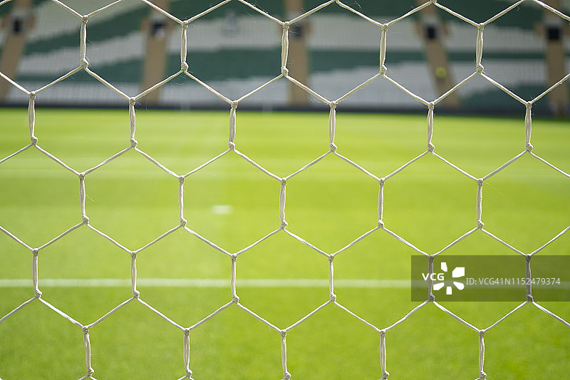 绿色草地上的足球网的特写，模糊了体育场的座位图片素材