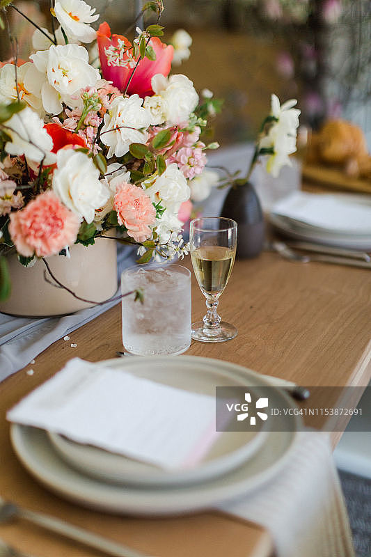 中世纪现代美丽风格的粉红色和婚礼花木制桌子上的位置设置和邀请图片素材
