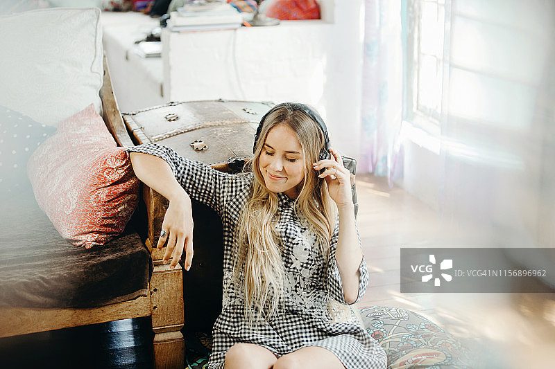 一个年轻女子坐在地板上戴着耳机听音乐图片素材