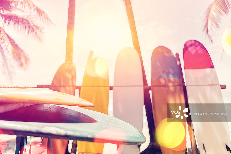 海滩上的冲浪板和棕榈树双重曝光，阳光光线纹理抽象的背景。暑假与运动极限概念。复古色调滤色风格。图片素材