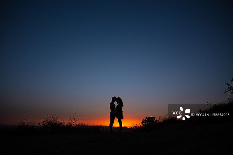 一对年轻夫妇在山上欣赏日落图片素材