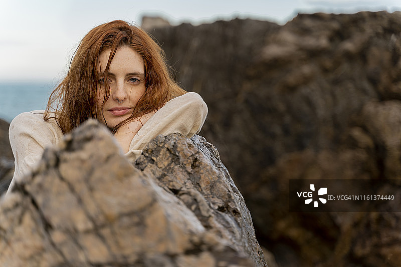 一幅靠在岩石上的红发年轻女子的肖像画图片素材