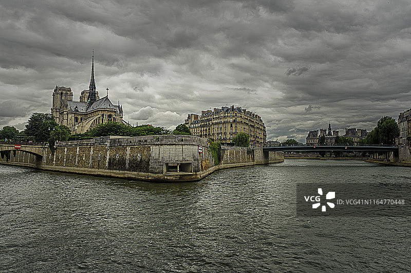 从后面看巴黎圣母院，在塞纳河上，背景是多云的图片素材