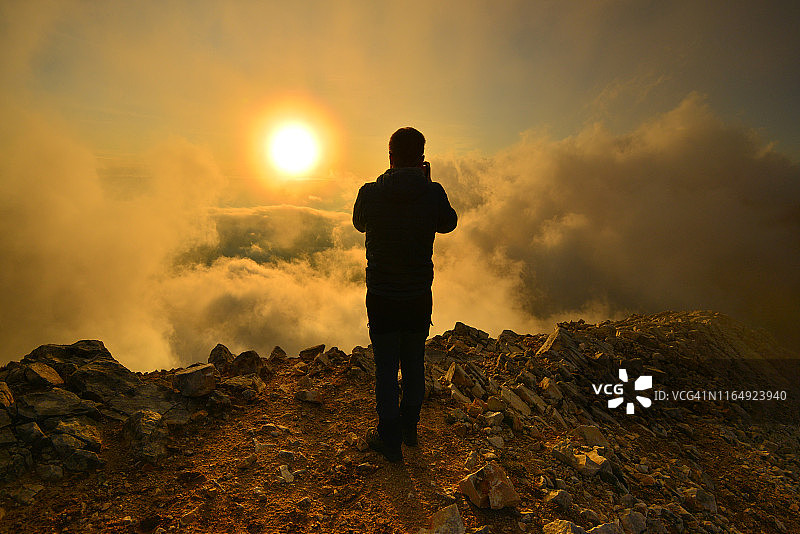 夕阳和人站在云雾缭绕的山顶上的美丽瞬间图片素材