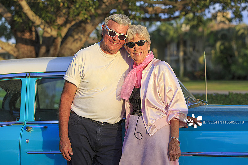 一对快乐的老年夫妇在汽车前的肖像图片素材