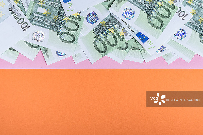 粉色和橙色背景的欧元现金。欧元纸币。欧元的钱。欧元的法案。文本。图片素材