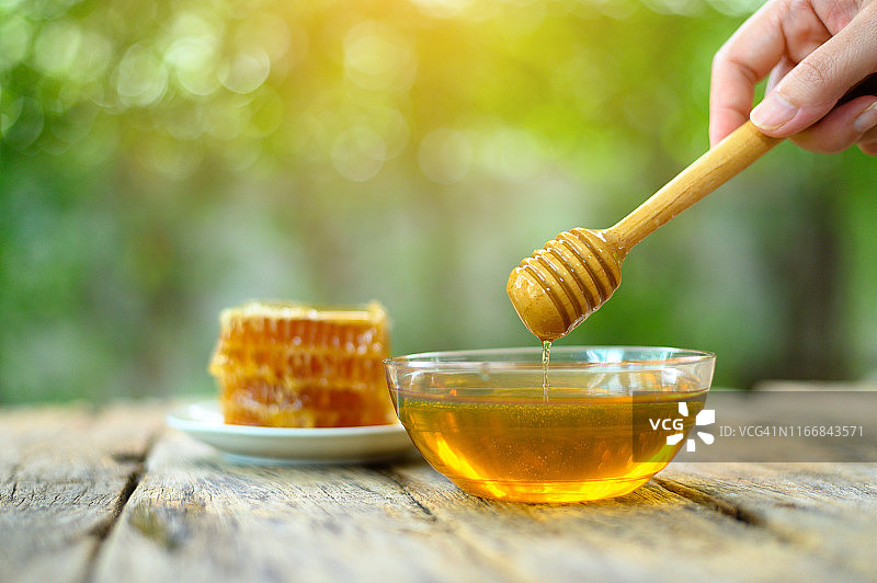 蜂蜜和木制蜂蜜勺放在木桌上图片素材