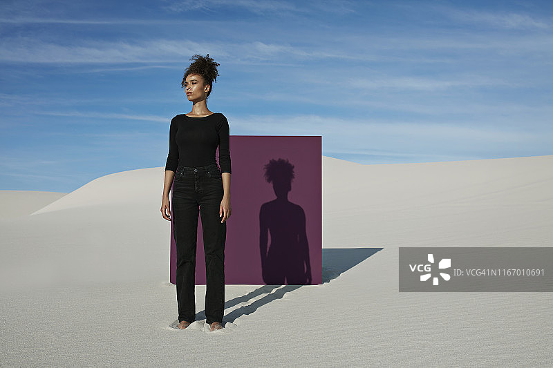 自信的年轻时装模特站在白色沙漠紫色的布告图片素材