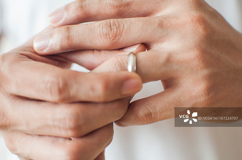 一个年轻人正在摘掉他的结婚戒指一个概念的关系困难图片素材