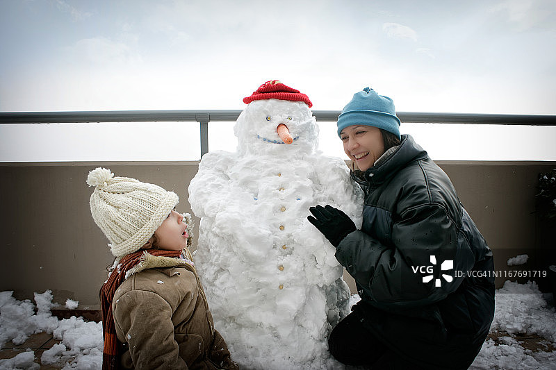 快乐的妈妈和女儿玩雪人的肖像图片素材
