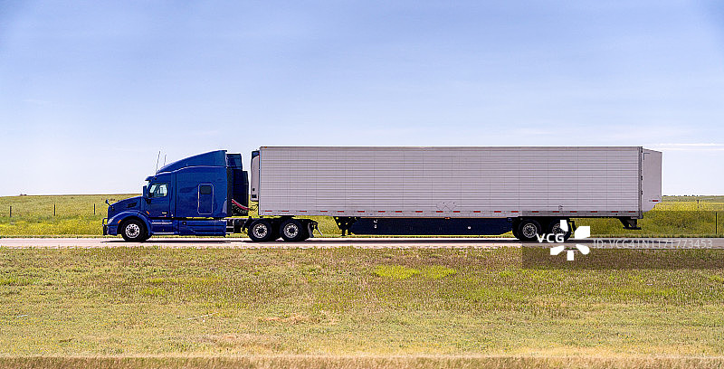 一辆长途半挂卡车在四车道公路上超速行驶的特写镜头图片素材