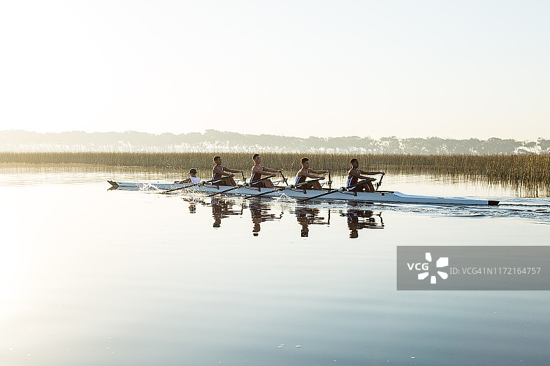 混合比赛青少年赛艇队训练在一个湖在黎明图片素材