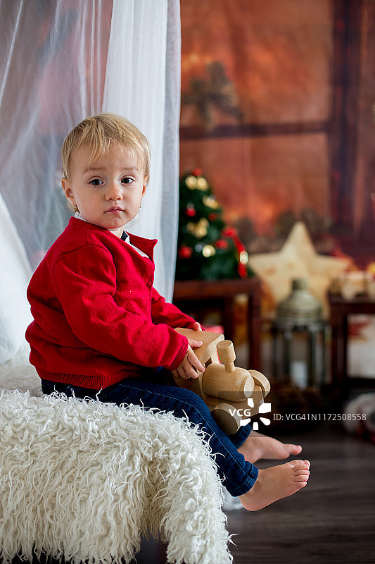 一个蹒跚学步的小女孩，圣诞节时坐在家里玩玩具图片素材