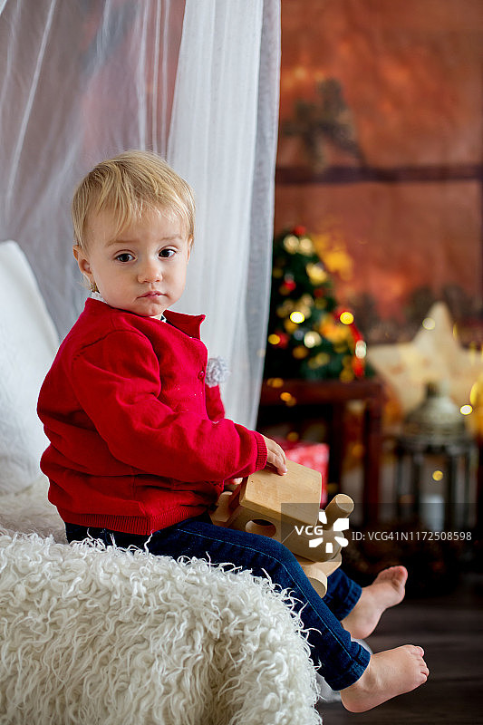 一个蹒跚学步的小女孩，圣诞节时坐在家里玩玩具图片素材