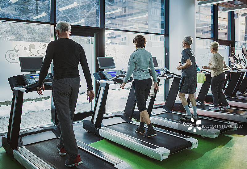 老人们在健身房里的跑步机上锻炼。图片素材