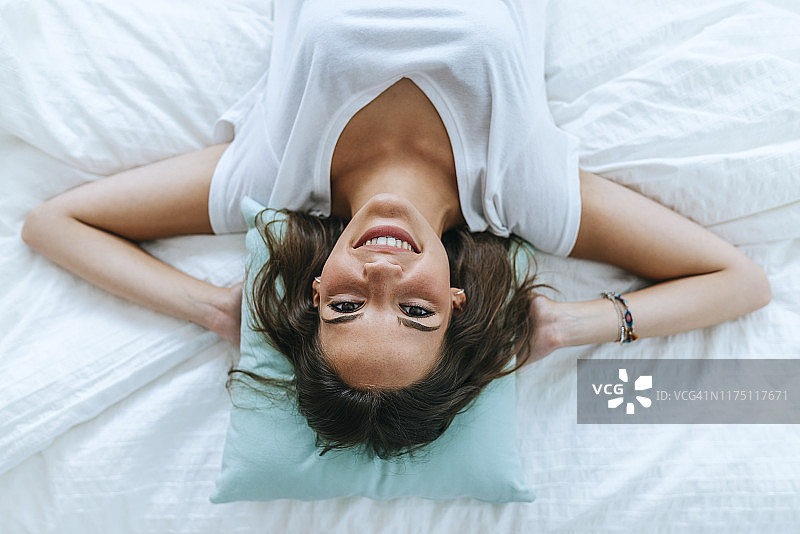 俯视图的幸福年轻女子躺在床上图片素材