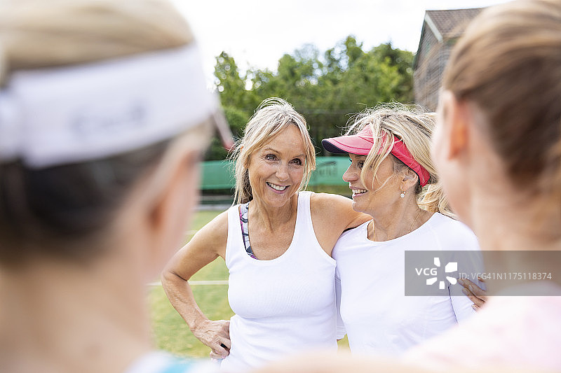 成熟的女人在网球俱乐部的草地上聊天图片素材